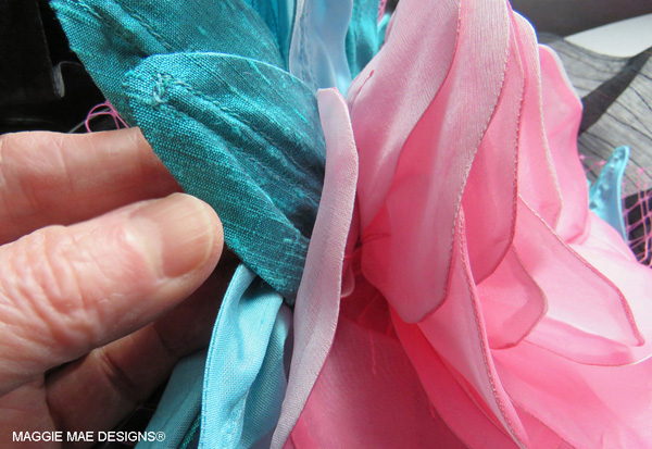 Two-tone teal dupioni silk leaves frame the flower on the "Cozmic One" hat design